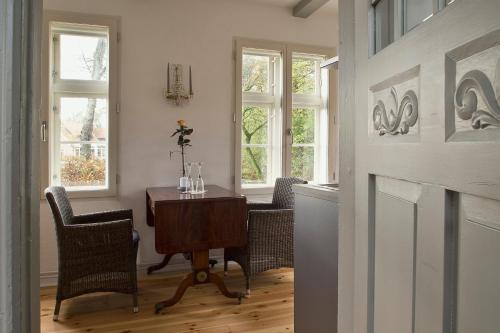 una sala da pranzo con tavolo, sedie e finestre di Gärtnerhaus a Cuxhaven