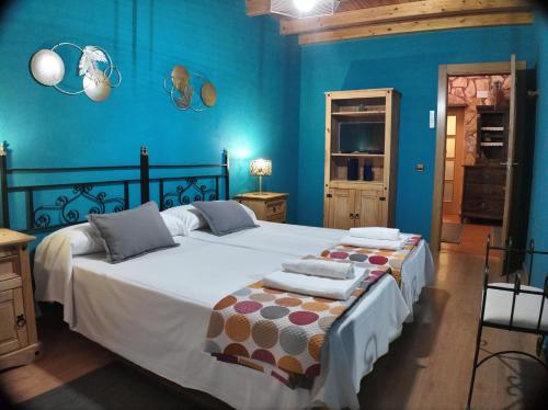 a bedroom with a large bed with blue walls at El Almendro del Cura in Villarmayor