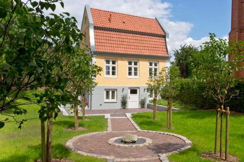 una casa amarilla con techo rojo en Gärtnerhaus en Cuxhaven