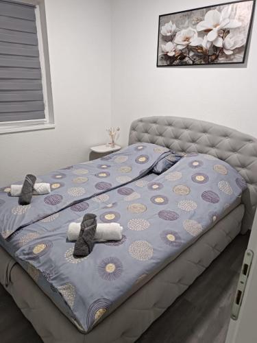 a bed with a blue comforter and two ties at Apartman Zana in Visoko