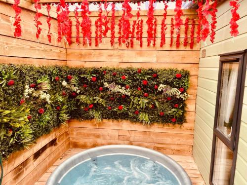 a wall with a garden with red flowers on it at Little Eden Country Park, Bridlington with Private Hot Tubs in Bridlington