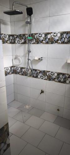een badkamer met douche en witte tegelvloeren bij FassoImmoPrestige in Tambacounda