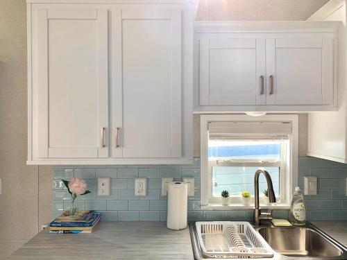 a kitchen with white cabinets and a sink and a window at Waterfront Tiny Home Pool Dock Kayaks Paddleboards in Key Largo