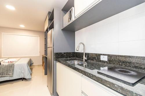 a kitchen with a sink and a bed in a room at Studio Completo Perto de Tudo - MUV0410 in Curitiba