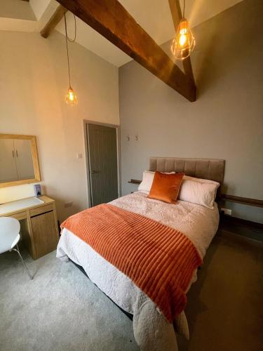 a bedroom with a bed with an orange blanket and a desk at The Annexe in Newark-on-Trent