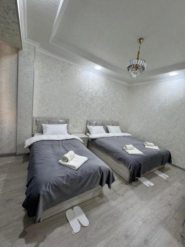 two beds in a room with slippers on the floor at Old Saroy Hotel in Samarkand