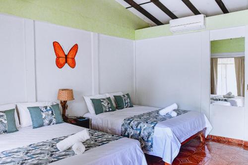 two beds in a room with a butterfly on the wall at Cabinas Bahía Uvita - Marino Ballena National Park Lodge in Uvita