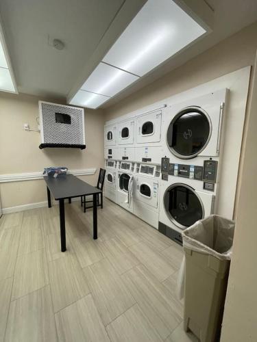 a laundry room with three washing machines and a table at Luxury Warehouse District Condo in Durham