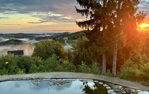 a pool of water with the sunset in the background at Das Gretlnest - Premium Naturrefugium in Gamlitz