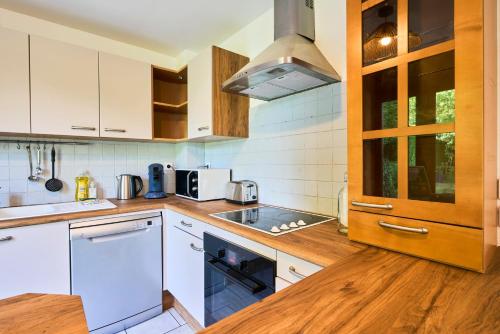 a kitchen with white cabinets and a wooden counter top at La Halte Verte - Garden -Wifi - Near Lille in Ennevelin