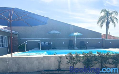 a swimming pool with two umbrellas next to a building at Casa Sol da Manhã - Piscina aquecida com hidromassagem - 300m da praia in Guaratuba