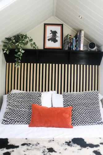 a bed with a black and white striped headboard and two pillows at Nant Cafn - Hafan Hideaways Eryri in Machynlleth