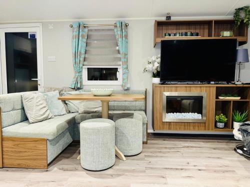 a living room with a couch and a table and a tv at Vinchella-3 bedroom caravan in Grange Over Sands