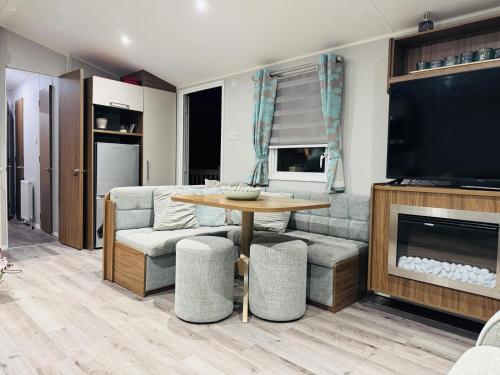 a living room with a couch and a table and a television at Vinchella-3 bedroom caravan in Grange Over Sands