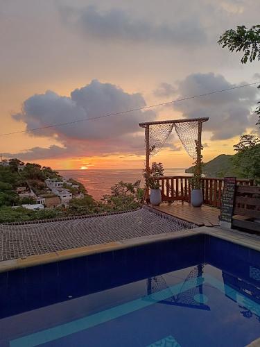 a swimming pool with a sunset in the background at Tayrona Colors Hostel in Taganga