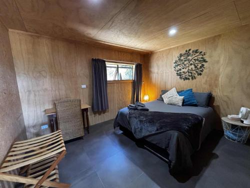 a bedroom with a bed and a table and a window at Motutangi Heights in Pukenui