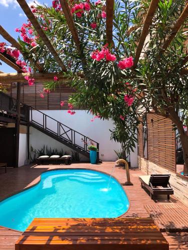 a swimming pool in a yard with a tree and pink flowers at Villa Puglia Jeri in Jericoacoara