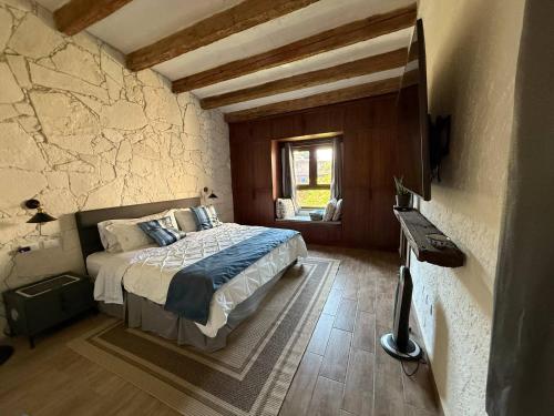 a bedroom with a bed in a room with a stone wall at Solange Suite en ValQuirico in Santeagueda