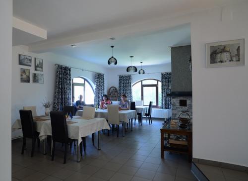 a dining room with tables and chairs and people at Vila Madudu in Vălenii de Munte