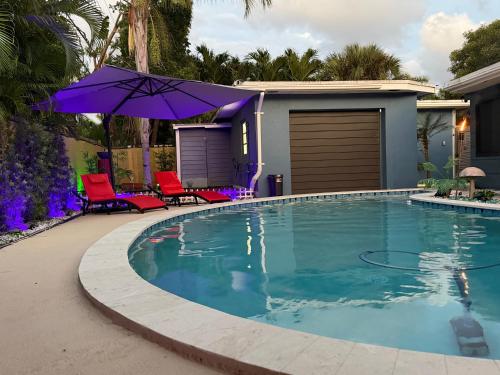 a swimming pool with two chairs and an umbrella at Den of Sin Guesthouse Wilton Manors FL in Fort Lauderdale