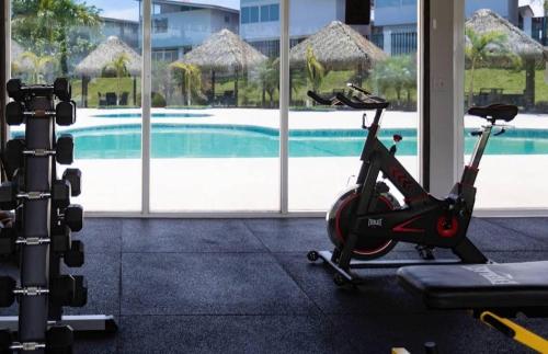 a gym with a fitness machine next to a swimming pool at Dia de playa en Paradise Point in Nueva Gorgona
