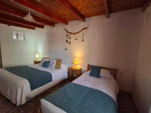 two beds in a room with wooden ceilings at Cabañas el Chañar in San Pedro de Atacama