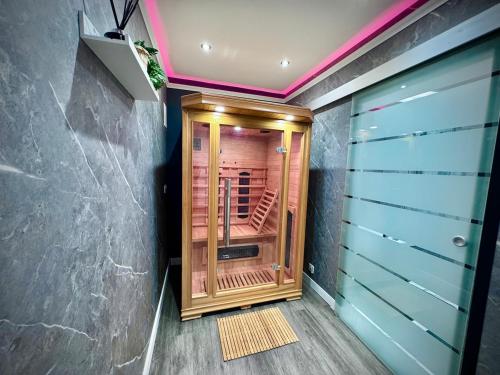 a walk in shower with a wooden door in a room at Suite 1 Private Jacuzzi Spa Hot Tub & Sauna in Attercliffe