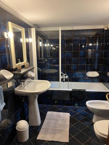 a blue tiled bathroom with two sinks and a tub at bilocale mirabilandia in Borgo Fosso Ghiaia