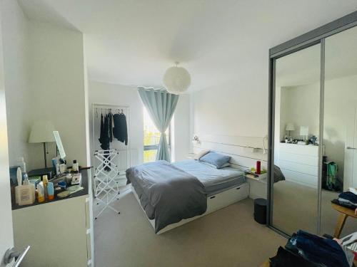 ein Schlafzimmer mit einem Bett und einem Spiegel in der Unterkunft Modern two-bedroom flat near Cambridge University Biomedical Campus in Trumpington