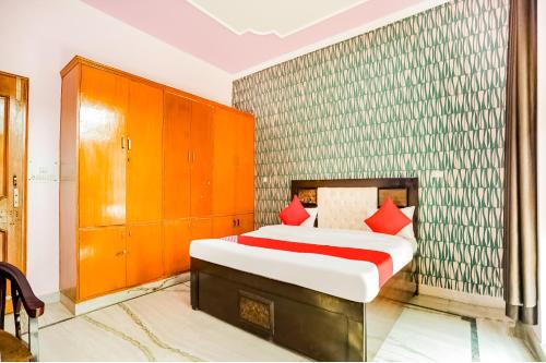 Un dormitorio con una cama con almohadas rojas. en Hotel O Royal Inn, en Faridabad