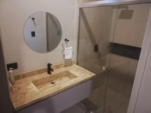 a bathroom with a sink and a mirror and a shower at A beautiful apartment, in the heart of the golden zone! in Mazatlán