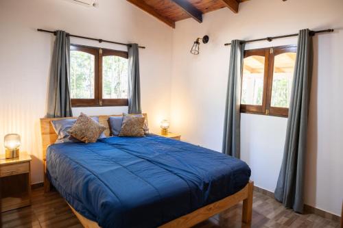 Estancia Estrella في Trinidad: غرفة نوم بسرير ازرق مع نافذتين