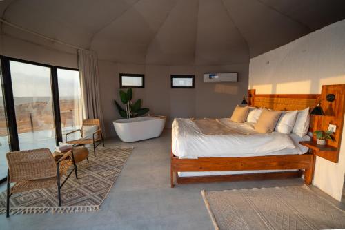 a bedroom with a bed and a tub in a room at Starry Domes Desert Camp in Badīyah