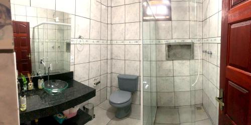 a bathroom with a toilet and a glass shower at Casa da Gabi - Hospedagem Familiar em Paraty in Paraty