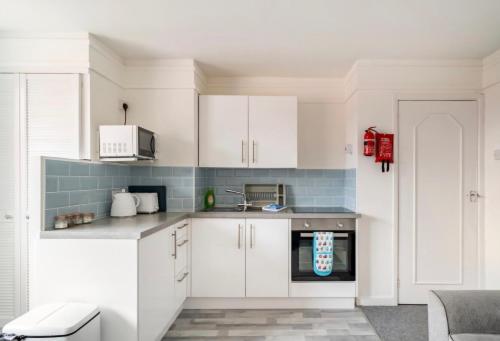 a kitchen with white cabinets and a red appliance at 45 New Esplanade Court in Paignton