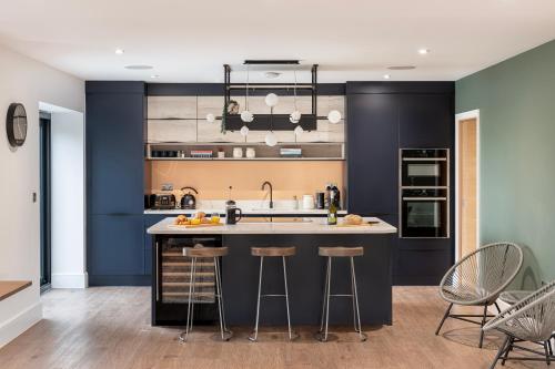 una cocina con paredes azules y una isla con taburetes. en Brockview House - Eco 4 bed, en Holcombe