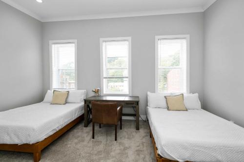 two beds in a room with a desk and windows at Cincy Comfort Retreat in Cincinnati