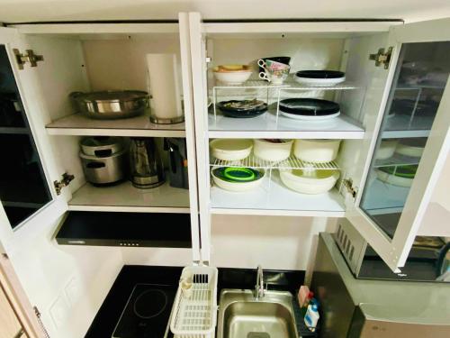 a kitchen cabinet filled with lots of dishes at Condo Stay Near SM City Santa Rosa Mall in Ibaba