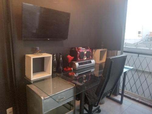 ペロタスにあるLoft central llのテレビとコンピューターが置かれたガラスの机