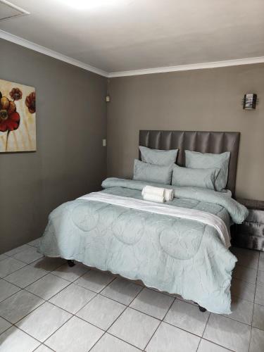 Schlafzimmer mit einem großen Bett mit blauer Decke in der Unterkunft Tranquil Leisure in Midrand