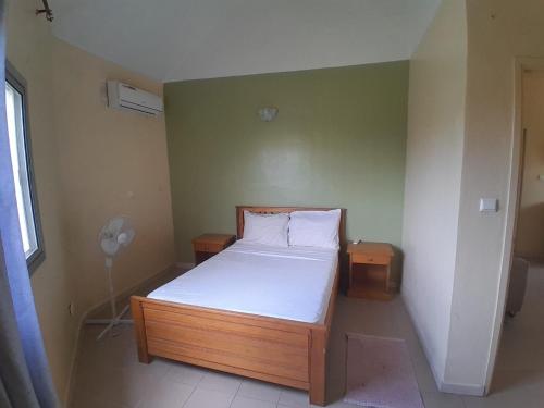 a small bedroom with a bed and a fan at Le Noflaye in Sali Nianiaral