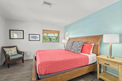 シエスタ・キーにあるBlue Ocean Suitesのベッドルーム1室(赤い掛け布団、椅子付)