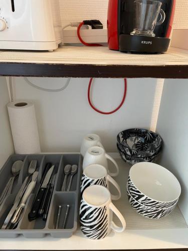 a shelf with dishes and utensils in a kitchen at En hauteur, au pied du métro & 7mn du centre Lille in Mons-en-Baroeul