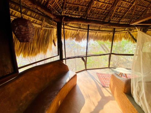 a room with a couch and a chair in a straw hut at Flor de Arena in Arroyo Cruz