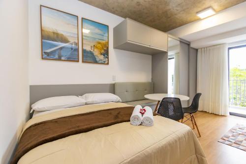 two beds in a room with a table and chairs at Studio Completíssimo Próximo a PUC PR - URB0403 in Curitiba