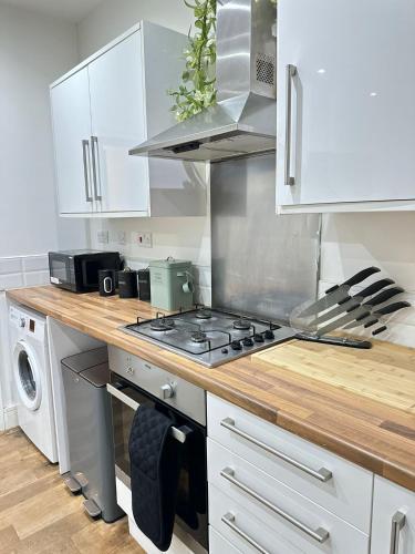 a kitchen with white cabinets and a stove top oven at Sky High Apartment in Streatham in London