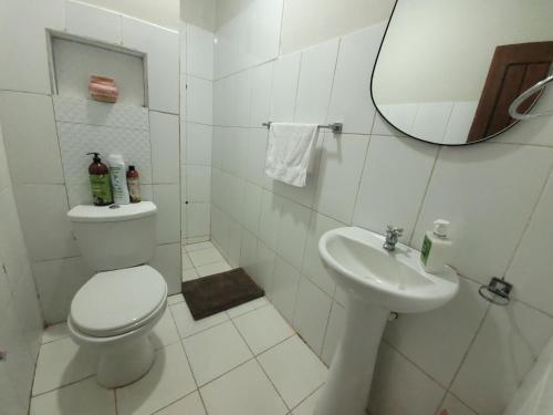 a white bathroom with a toilet and a sink at El Bullicio de la Cabaña in Iquitos