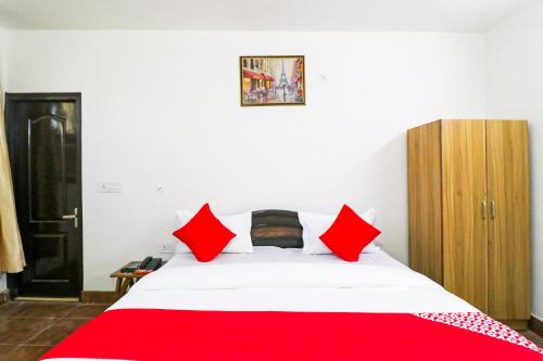 a bedroom with a white bed with red pillows at Hotel O Cloud Stay & Cafe in Indraprast