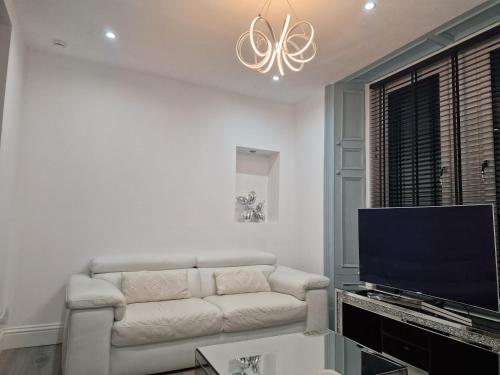 a living room with a couch and a flat screen tv at Boutique villa newly refurbished Dundee in Dundee