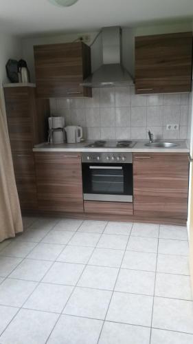 a kitchen with wooden cabinets and a stove top oven at Ferienwohnung Roeben in Simmerath